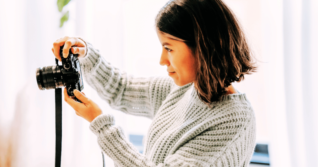 Woman photographing in cozy setting with camera, focused on creative passion.