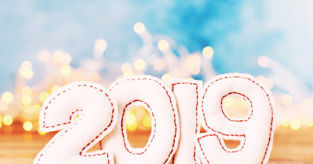 Festive 2019 plush numbers with twinkling lights and serene blue gradient background.