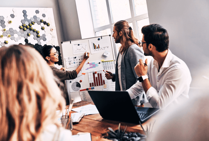Collaborative business meeting with data presentation and team discussing performance trends portraying why executive coaching is essential for new world leadership demands..
